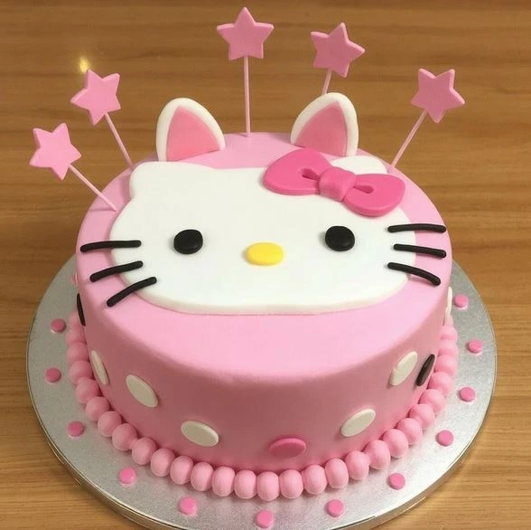 Pink Hello Kitty cake with white polka dots, fondant Hello Kitty face, pink bow, and star-shaped toppers.